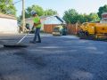 A Superior Asphalt team member rakes out fresh asphalt on a new driveway in Winnipeg