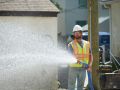 A Superior Asphalt team member hoses down a patch of gravel to pack it tightly