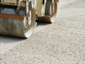 Using heavy steamrollers to flatten and smooth out gravel prior to paving